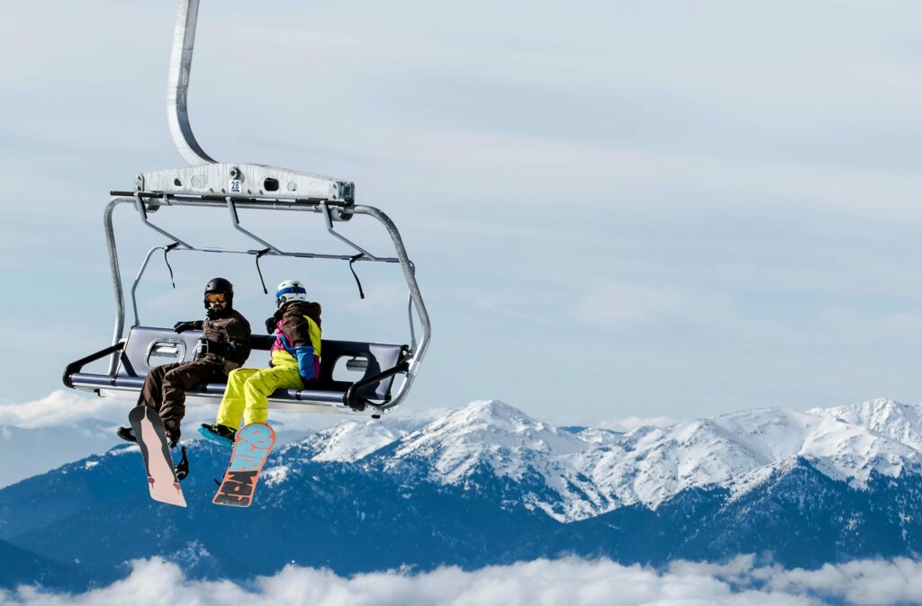 Two skiers riding a chairlift with mountains in the background